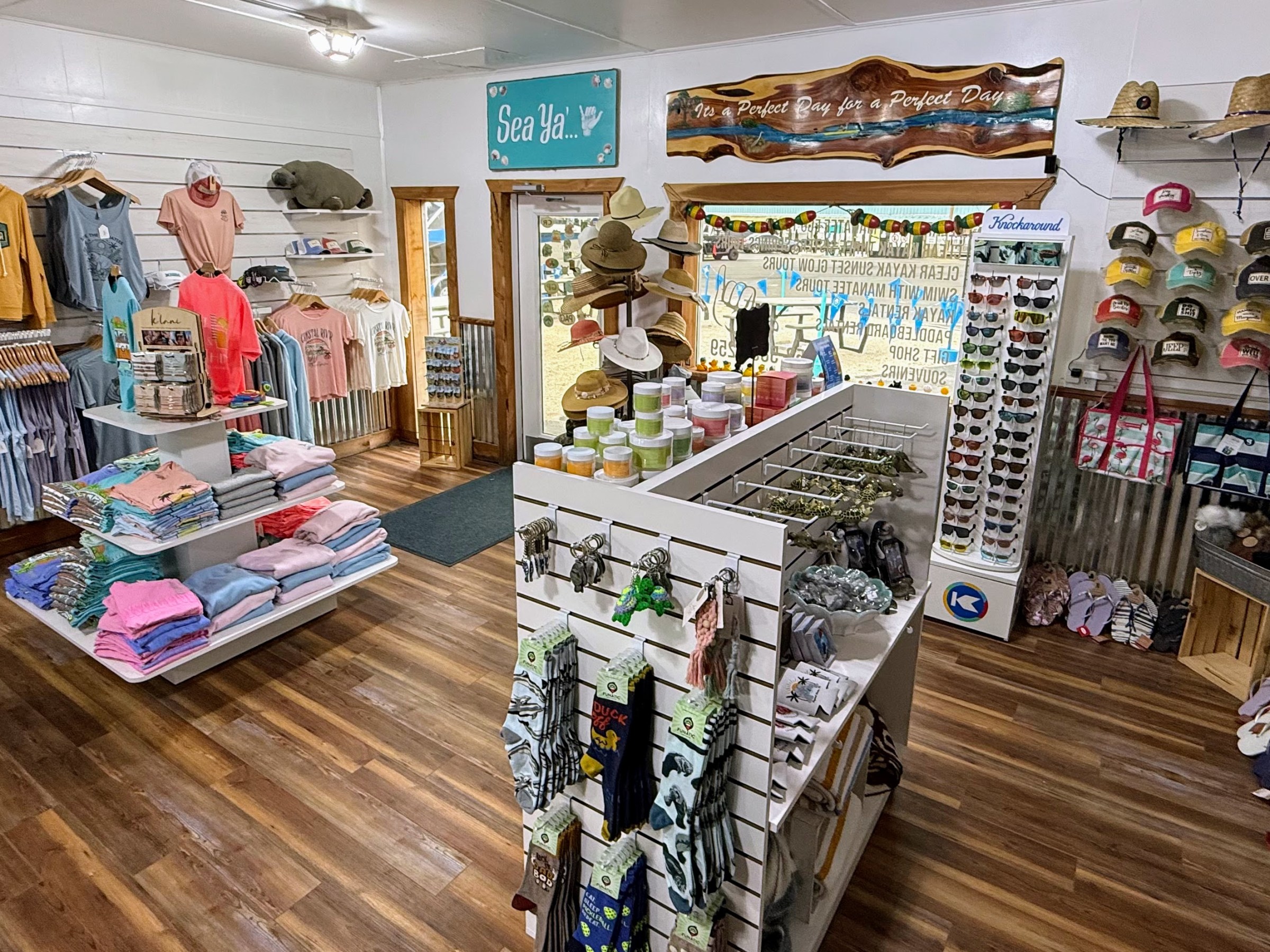 Clothing and accessory store with shirts, hats, sunglasses, and beachwear on display.