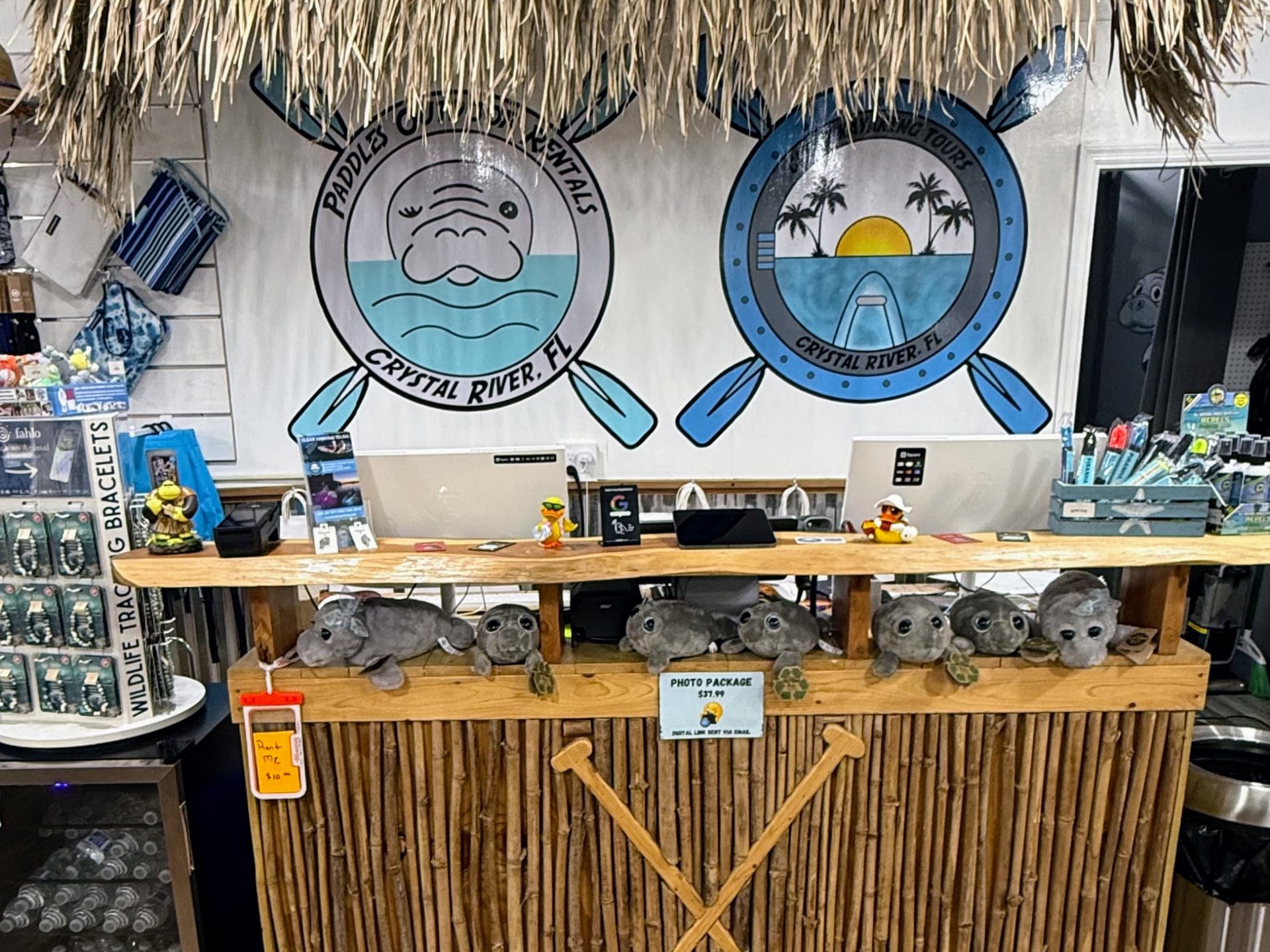 Tropical-themed rental shop counter with manatee plushies, bamboo decor, and paddle logos.