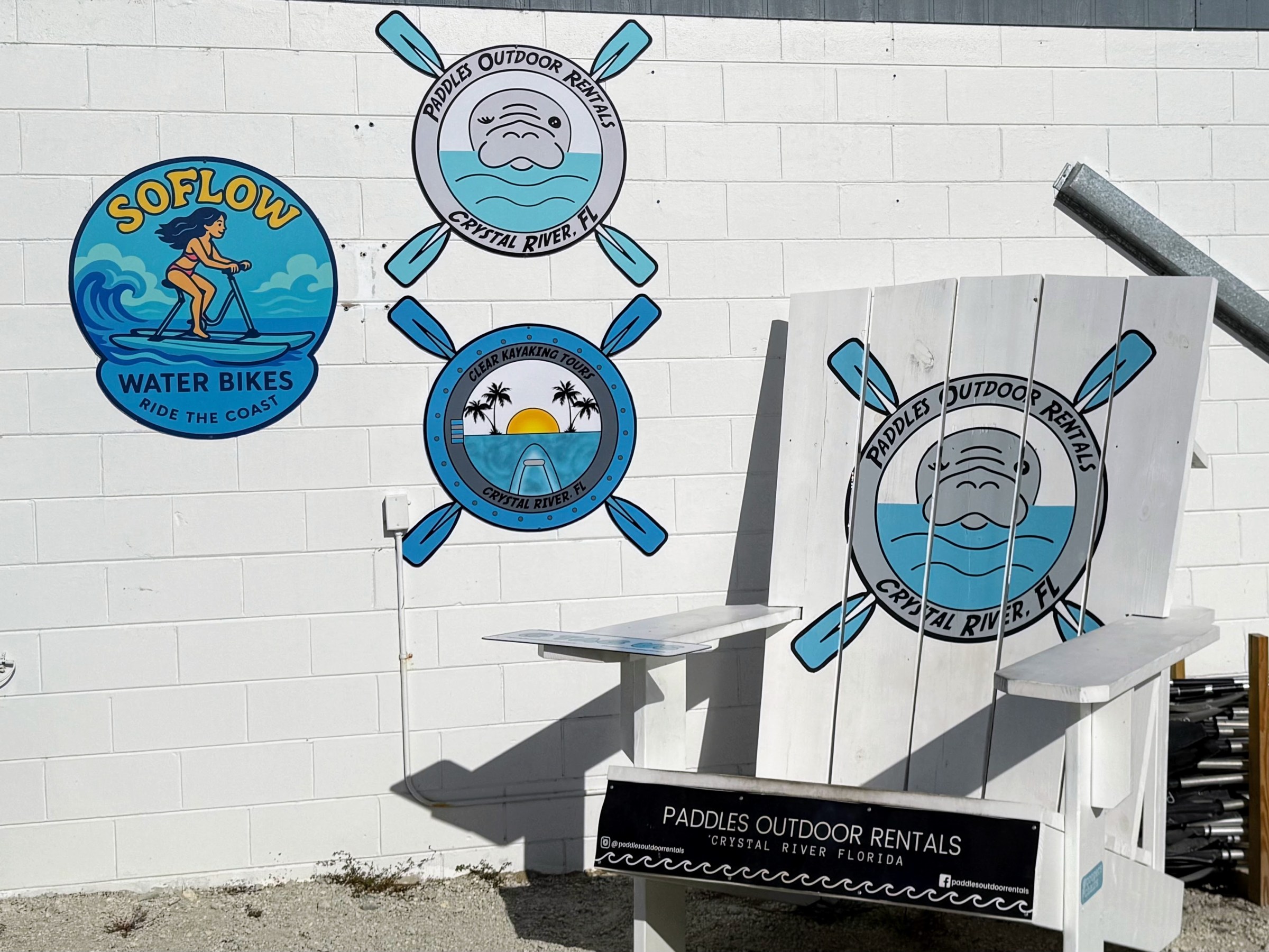 Wall with outdoor rental logos and a large wooden chair featuring paddle designs.